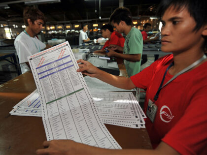 A Smartmatic employee shows a ballot paper after testing it on a election automated machin