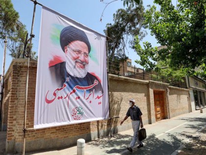 An Iranian man walks past an electoral poster depicting judiciary chief and presidential c