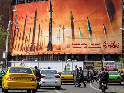 Motorists drive their vehicles past a billboard depicting named Iranian ballistic missiles