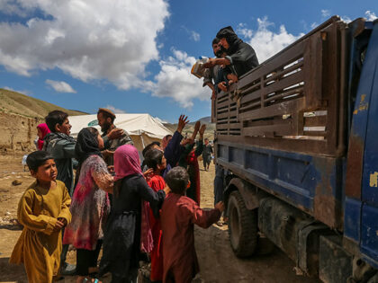 Children queue next to a truck to recieve aid after the flash floods in the Borka village