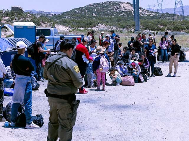 A U.S. Border Patrol agent watches over asylum seekers at the U.S.-Mexico border on June 8