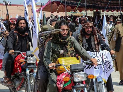 Taliban security personnel holding rocket-propelled grenade (RPGs) ride motorbikes as they