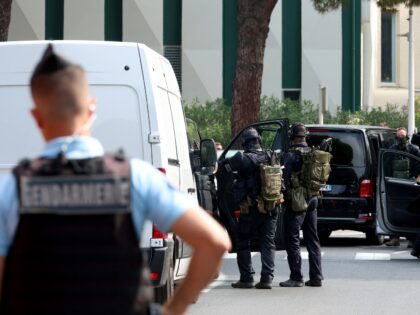 Law enforcement officers stand in front of a synagogue, in background on the right on the