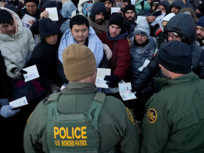 Border Patrol agents ask asylum-seeking migrants to line up in a makeshift, mountainous ca