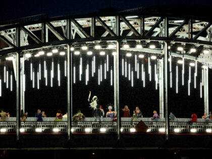 PARIS, FRANCE - JULY 26: Mysterious Torchbearer holds the Olympic Torch while on a bridge