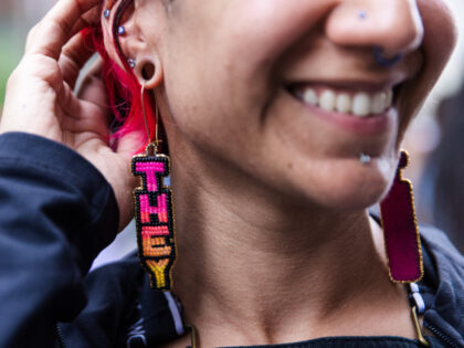 hine shows pronoun earrings they make and sell at theTrans march. Several thousand people