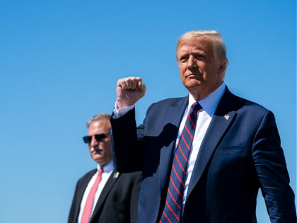 President Donald J. Trump gestures with a fist-pump as he disembarks Air Force One at Wilk